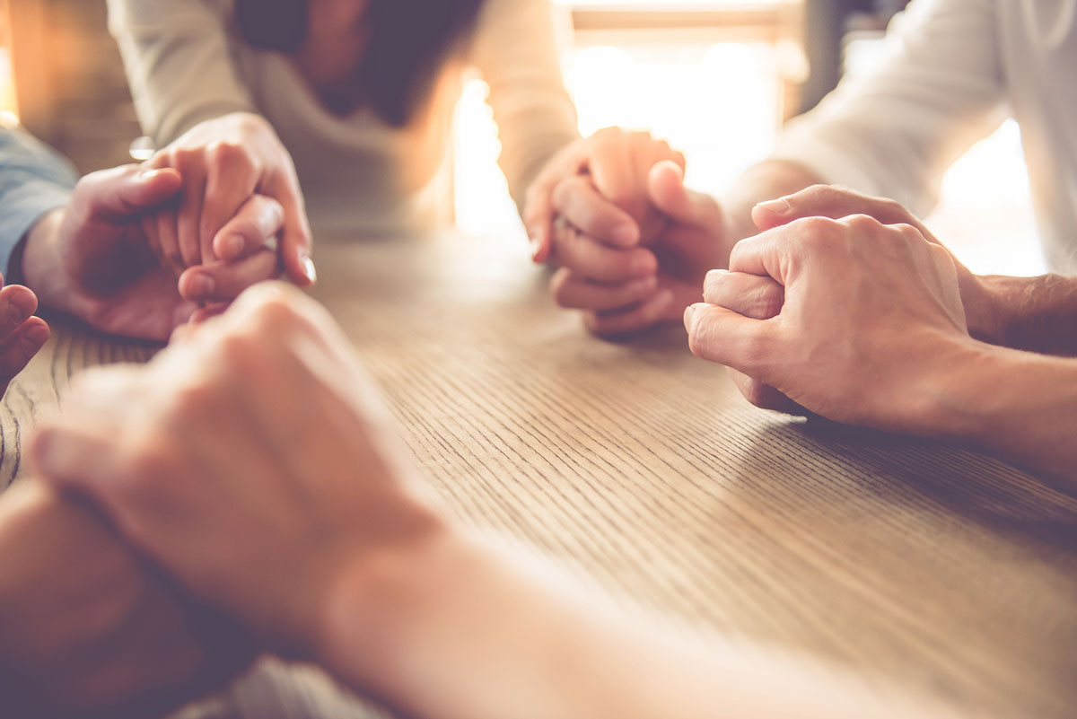 People around table holding hands